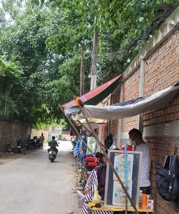 一位在寺庙围墙边理发商贩每天收入约25美元